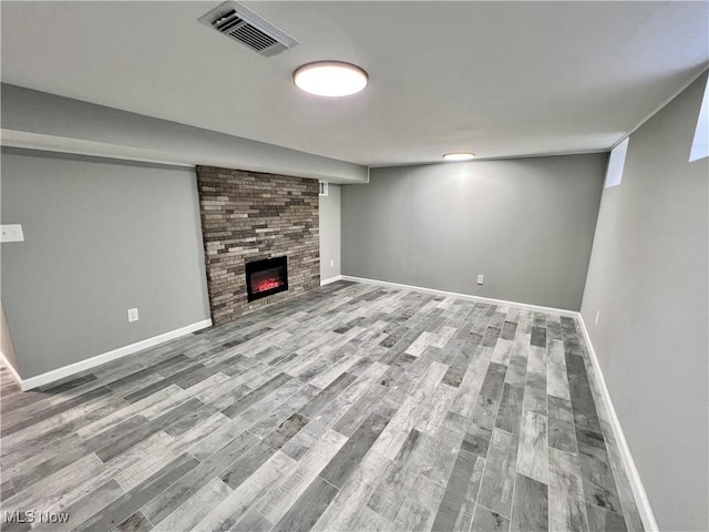 basement with a large fireplace and wood-type flooring