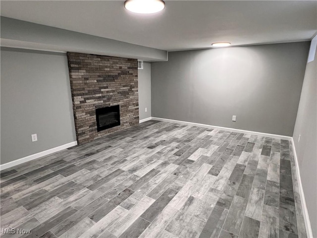 basement with a stone fireplace and wood-type flooring