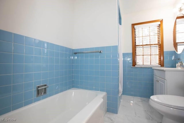 bathroom featuring a bathing tub, vanity, toilet, and tile walls