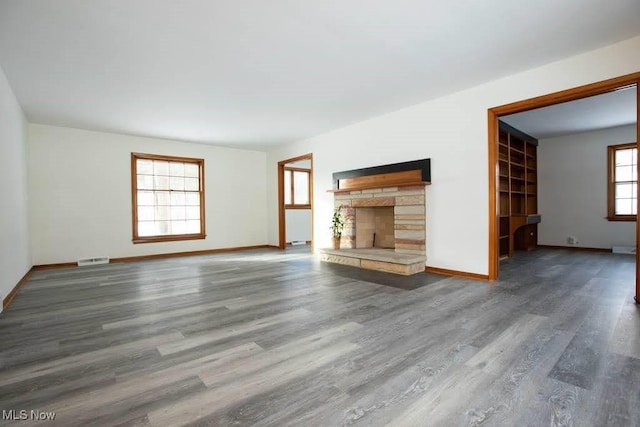 unfurnished living room with hardwood / wood-style floors and a stone fireplace