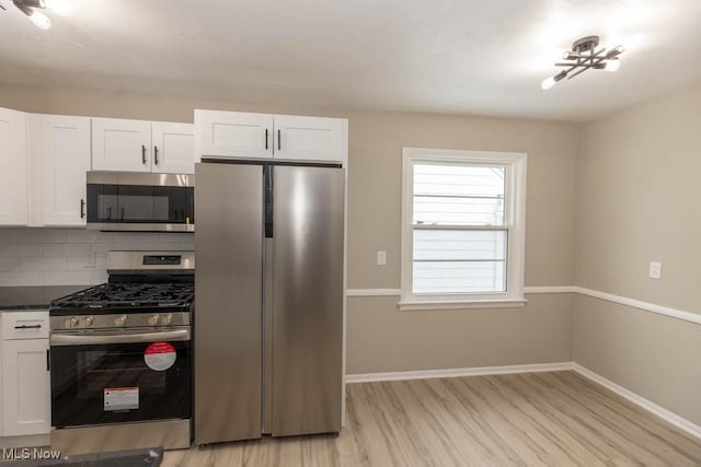 kitchen with stainless steel appliances, tasteful backsplash, light hardwood / wood-style flooring, dark stone countertops, and white cabinets