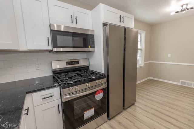 kitchen with dark stone counters, tasteful backsplash, white cabinets, and stainless steel appliances