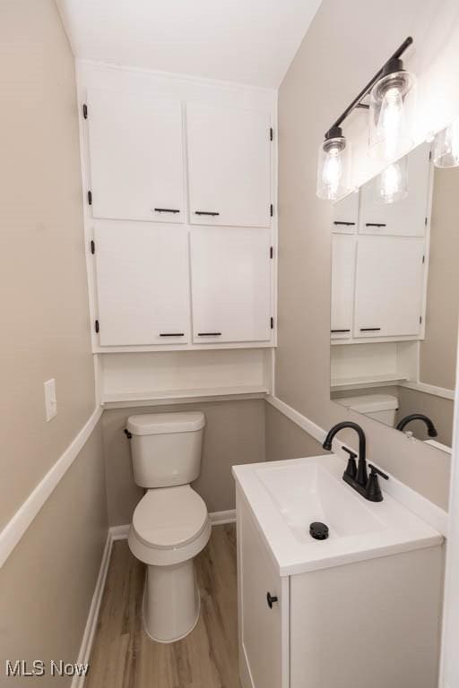 bathroom with hardwood / wood-style floors, vanity, and toilet