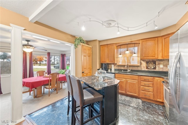 kitchen featuring sink, a breakfast bar area, ceiling fan, tasteful backsplash, and stainless steel appliances