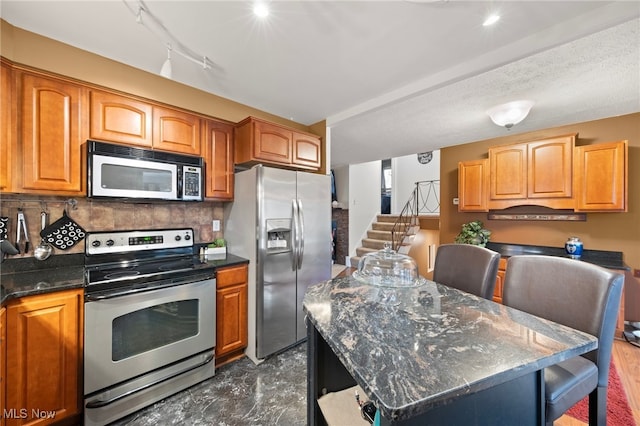 kitchen with backsplash, dark stone counters, stainless steel appliances, and a kitchen island