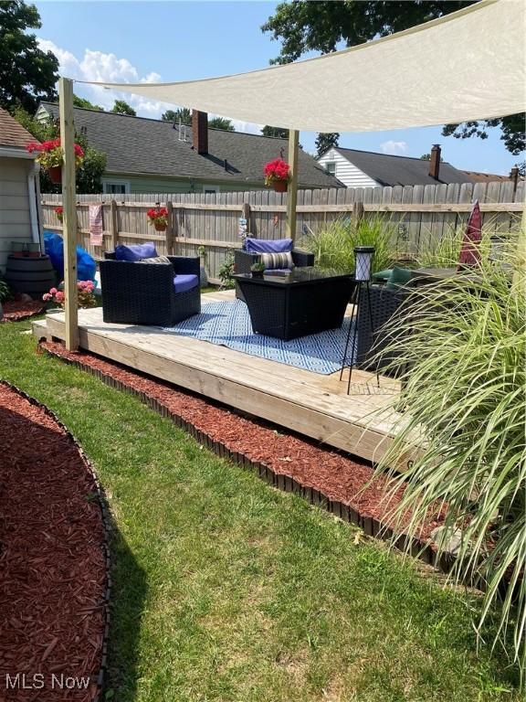 wooden terrace with an outdoor hangout area and a lawn