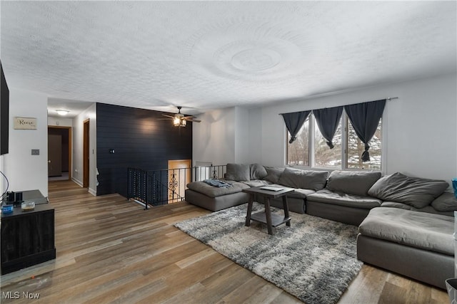 living room featuring hardwood / wood-style floors, ceiling fan, and a textured ceiling