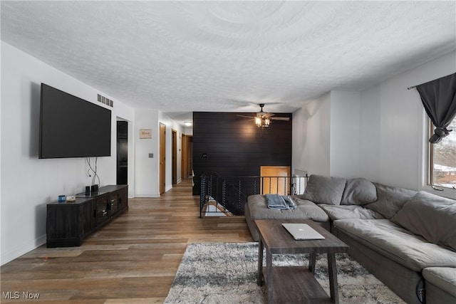 living room featuring ceiling fan, wood-type flooring, and a textured ceiling