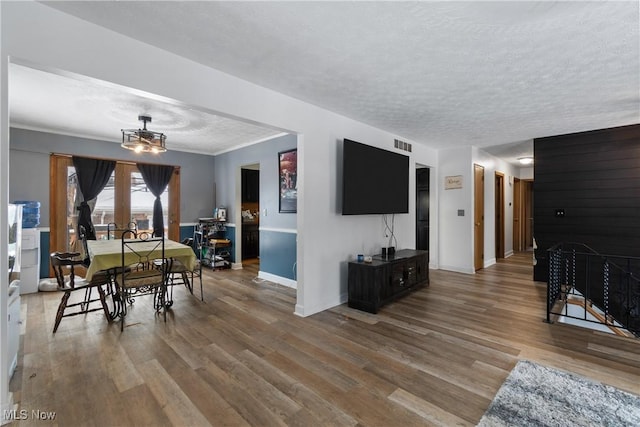 living room with a chandelier, wood-type flooring, a textured ceiling, and ornamental molding