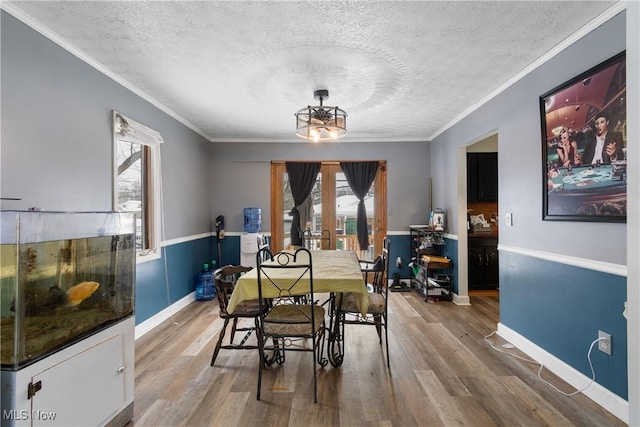 dining area with a notable chandelier, a healthy amount of sunlight, wood-type flooring, and a textured ceiling