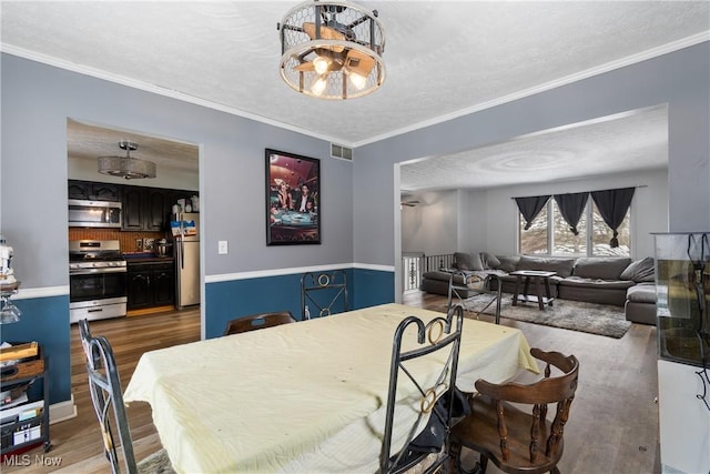 dining area featuring a textured ceiling, light hardwood / wood-style floors, and ornamental molding