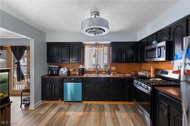 kitchen featuring sink, light hardwood / wood-style floors, a textured ceiling, and appliances with stainless steel finishes