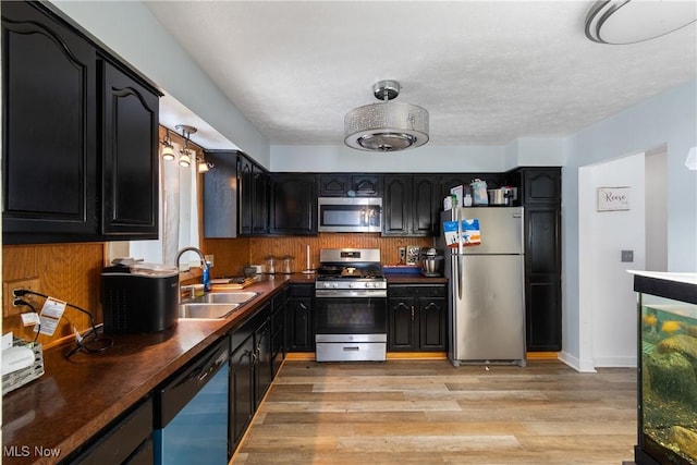 kitchen featuring sink, a textured ceiling, light hardwood / wood-style floors, butcher block counters, and stainless steel appliances