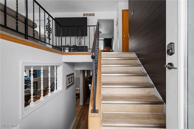 staircase with wood walls and wood-type flooring