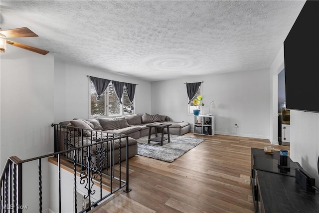 living room with hardwood / wood-style flooring, ceiling fan, and a textured ceiling