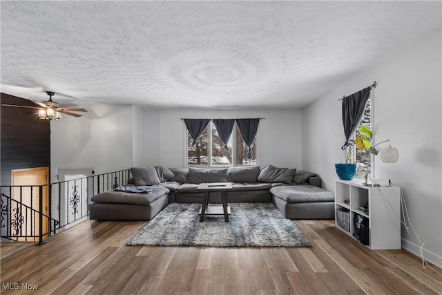 living room featuring ceiling fan, wood-type flooring, and a textured ceiling