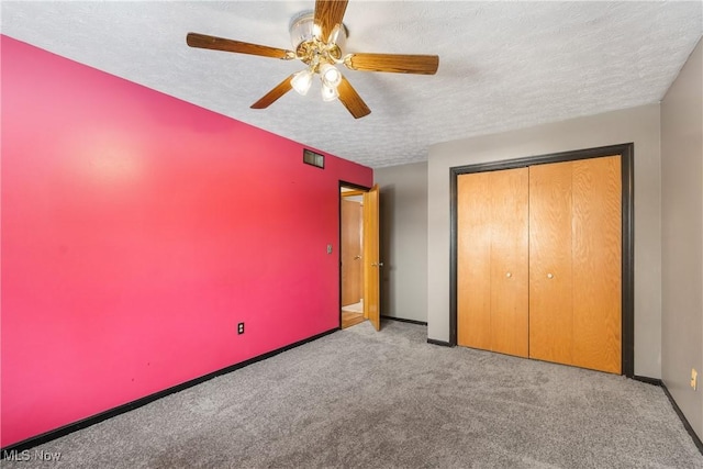 unfurnished bedroom with ceiling fan, light colored carpet, a textured ceiling, and a closet