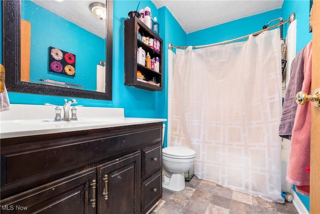 bathroom with vanity, toilet, and a textured ceiling