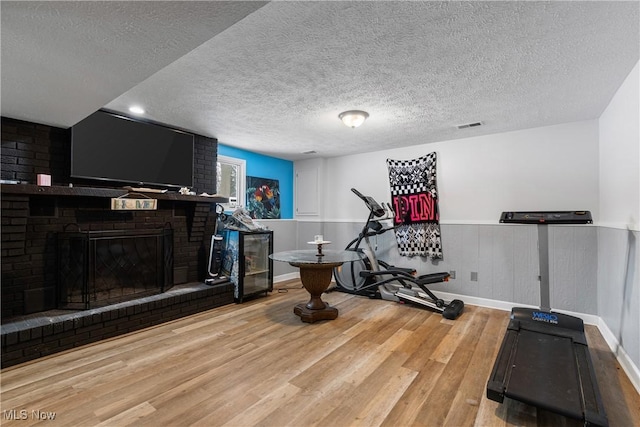 workout room featuring a fireplace, a textured ceiling, and hardwood / wood-style flooring