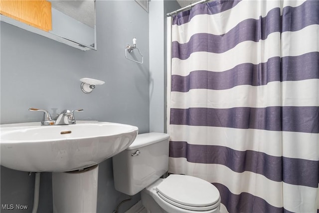 bathroom with a shower with shower curtain, toilet, and a textured ceiling