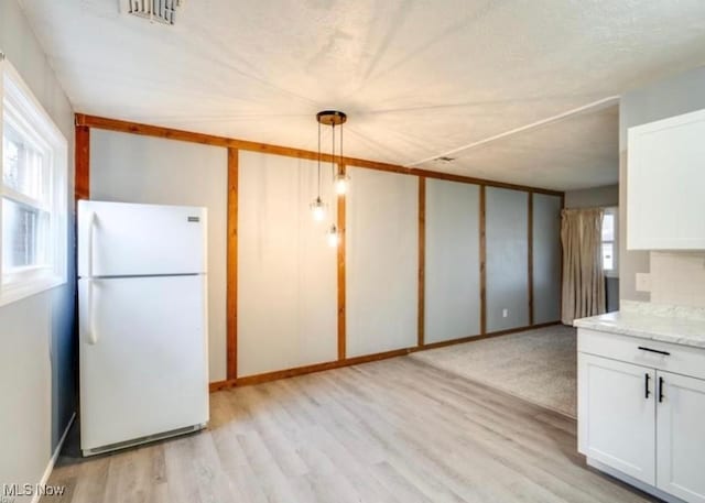 kitchen with white cabinets, backsplash, white fridge, and hanging light fixtures