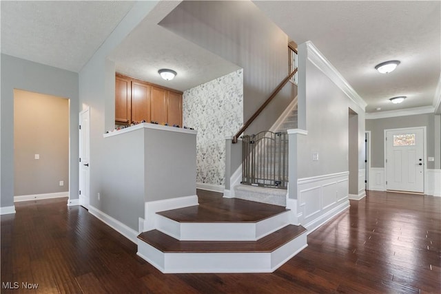 staircase with hardwood / wood-style floors, a textured ceiling, and ornamental molding