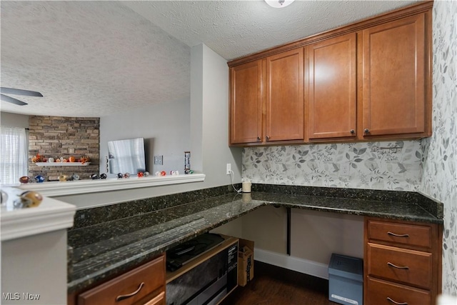 kitchen featuring a textured ceiling, ceiling fan, and dark stone counters