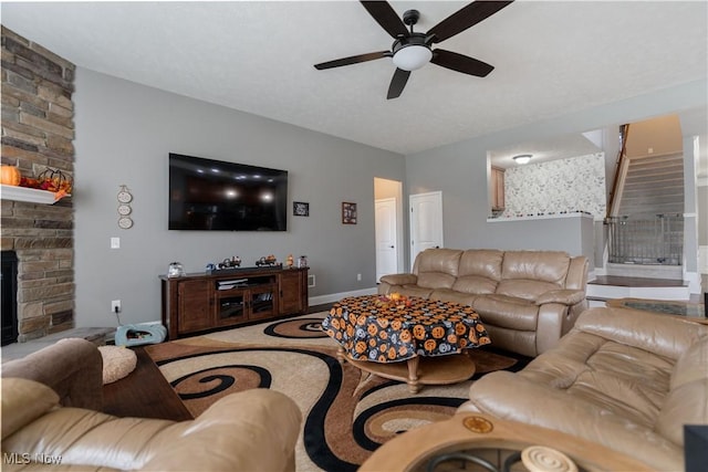 living room featuring a stone fireplace and ceiling fan