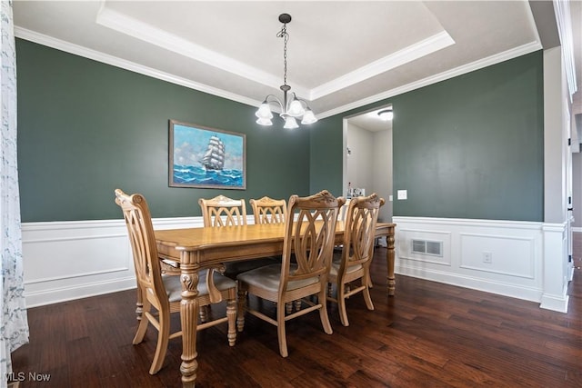 dining space with a raised ceiling, dark wood-type flooring, and a notable chandelier