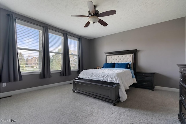 bedroom with ceiling fan, light colored carpet, and a textured ceiling