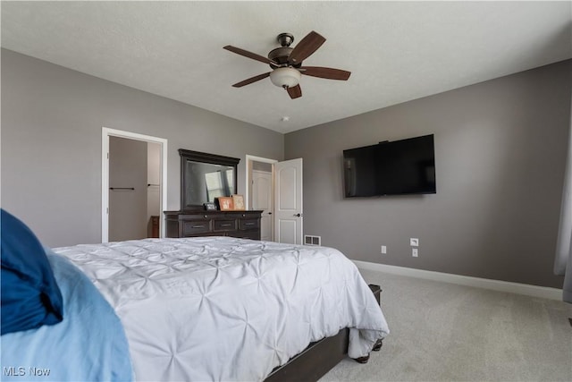 carpeted bedroom with ceiling fan and a spacious closet