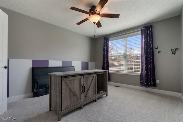 carpeted office space featuring a textured ceiling and ceiling fan