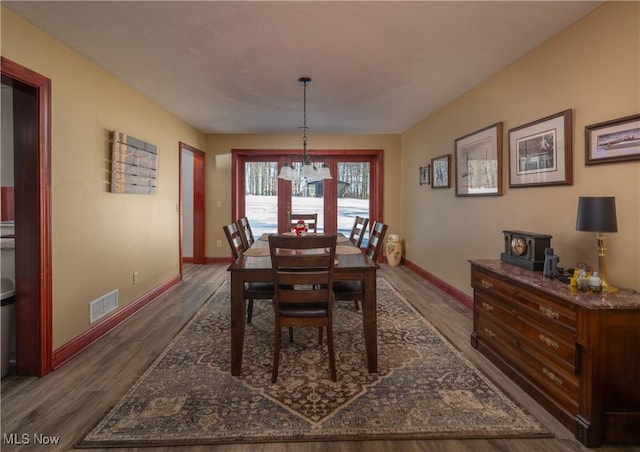 dining space with a chandelier and dark wood-type flooring