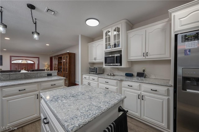 kitchen featuring decorative light fixtures, stainless steel appliances, and white cabinetry