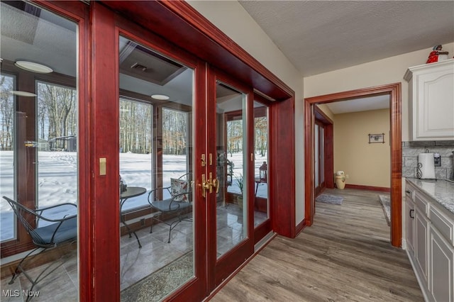 doorway with french doors, a textured ceiling, and light wood-type flooring