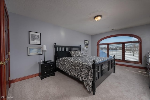 bedroom with light colored carpet and a textured ceiling