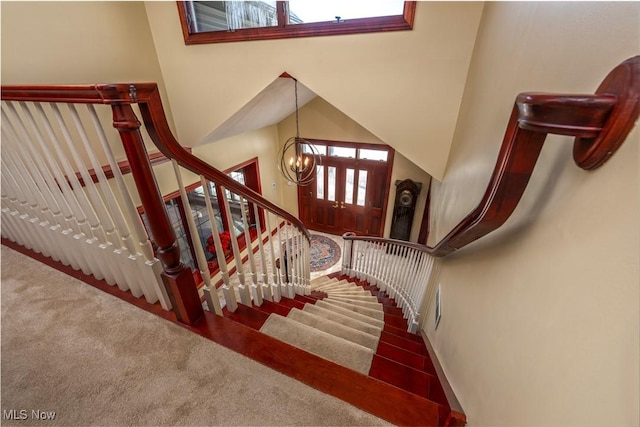 stairway featuring carpet flooring, a wealth of natural light, and a chandelier