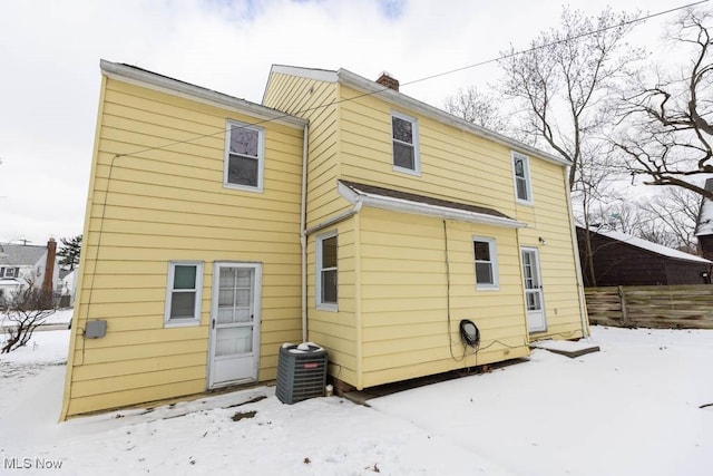 snow covered rear of property featuring central air condition unit