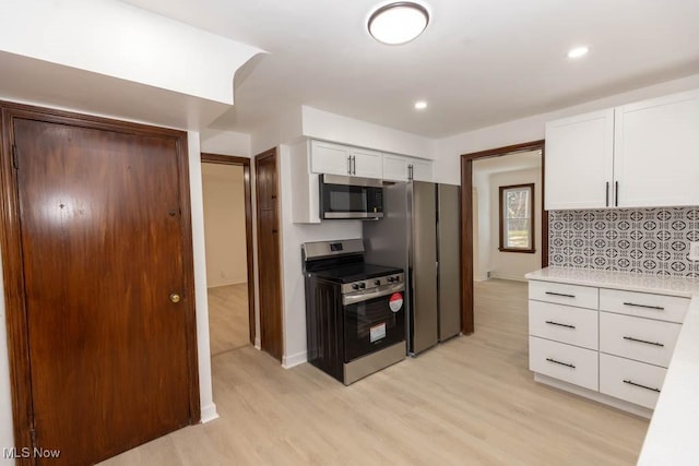 kitchen with decorative backsplash, white cabinets, stainless steel appliances, and light wood-type flooring