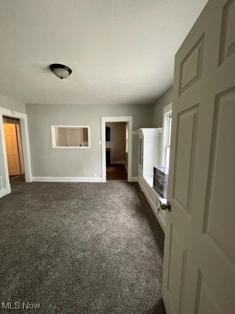 unfurnished living room with dark carpet