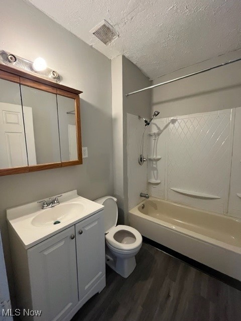 full bathroom featuring toilet, shower / tub combination, wood-type flooring, a textured ceiling, and vanity