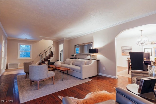 living room featuring hardwood / wood-style floors, ornamental molding, a textured ceiling, and a chandelier