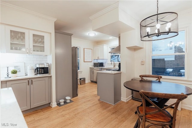 kitchen with tasteful backsplash, light hardwood / wood-style flooring, crown molding, a chandelier, and pendant lighting