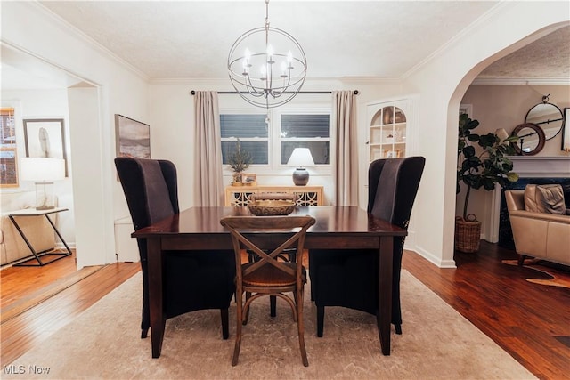 dining room featuring wood-type flooring, a textured ceiling, an inviting chandelier, and crown molding