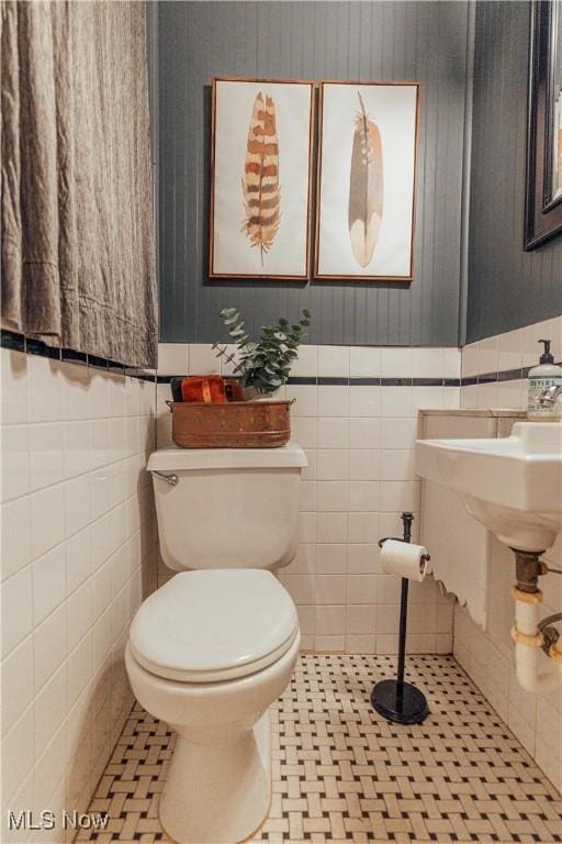 bathroom with tile patterned floors, toilet, and tile walls