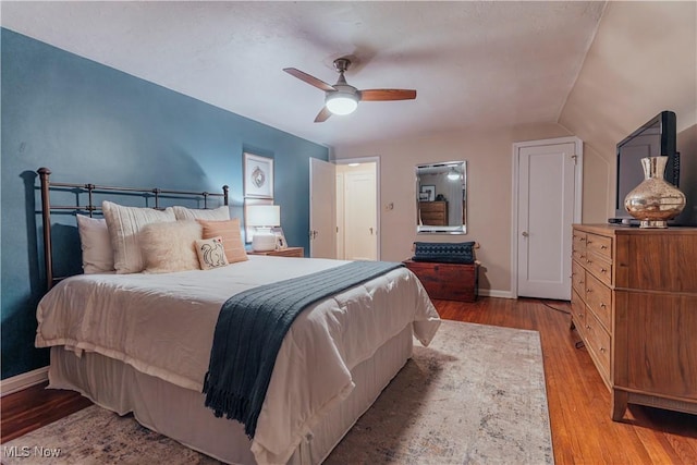 bedroom featuring light hardwood / wood-style floors, vaulted ceiling, and ceiling fan