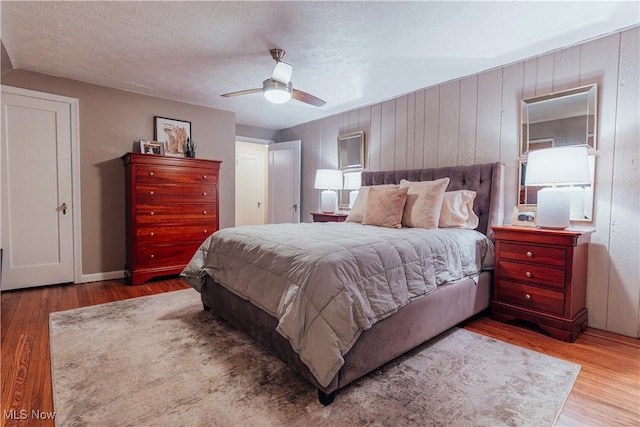 bedroom with ceiling fan, a textured ceiling, and hardwood / wood-style flooring