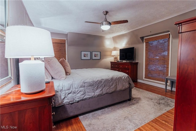 bedroom featuring ceiling fan, a textured ceiling, and light wood-type flooring