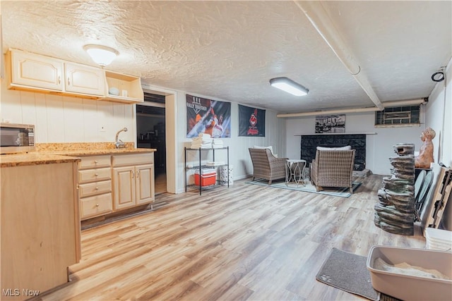 interior space featuring sink, light brown cabinets, a textured ceiling, and light wood-type flooring