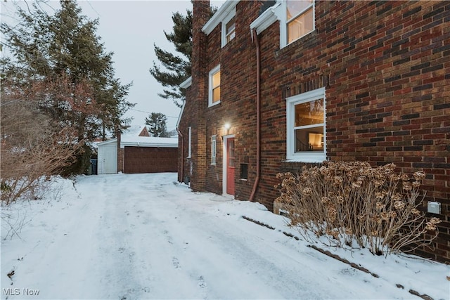 snow covered property with an outbuilding and a garage